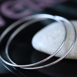 May include: Two silver hoop earrings with a textured surface.