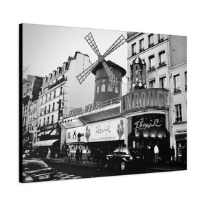 May include: A black and white photograph of the Moulin Rouge in Paris, France. The iconic windmill and red sign are visible, along with the words "Moulin Rouge" and "Féerie" in neon lights.
