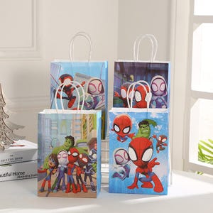 May include: Four blue gift bags with white paper handles. Each bag features a different Spider-Man character design. The bags have a light blue background with cityscapes and superhero illustrations. Ideal for party favours or gifts.