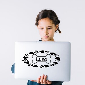 May include: A white laptop with a black paw print and heart design around a bone with the name "Luna" on it.