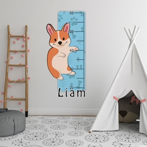 May include: A blue and white growth chart with paw prints and bones features a cartoon corgi dog. The chart is labelled with numbers from 20 to 60 and the name "Liam" is printed at the bottom.