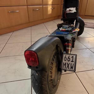 Könnte beinhalten: Schwarzer Elektroroller mit rotem Rücklicht und Nummernschild "661 MXW". Die Komponenten des Rollers sind freigelegt, Werkzeuge und Kabel sind sichtbar. Der Roller hat einen schwarzen Kotflügel und einen schwarzen Reifen.