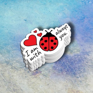 May include: A stack of white stickers with a red heart, a ladybug with black spots, and the text "I am with you always".