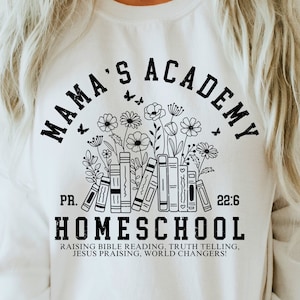 May include: White sweatshirt with black text that reads "Mama's Academy" in a circular design with a floral border and the words "PR. 22:6" and "Homeschool" below. The text below "Homeschool" reads "Raising Bible Reading, Truth Telling, Jesus Praising, World Changers!"