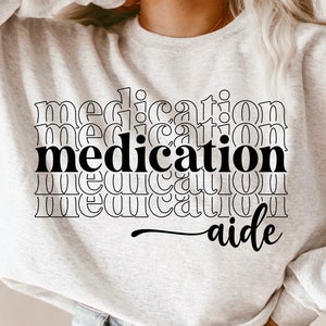 May include: A white sweatshirt with the text "medication aide" printed in black. The word "medication" is repeated multiple times in a stacked design.