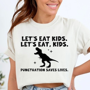 Pode incluir: Camiseta branca com um gráfico de dinossauro preto e o texto "Let's eat kids. Let's eat, kids. Punctuation saves lives."
