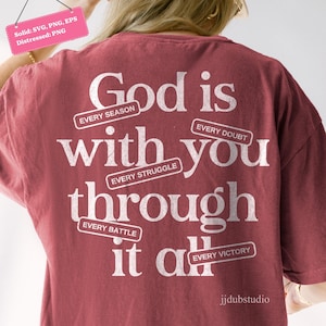 May include: A maroon t-shirt with the text "God is with you through it all." The text is in white, with the words "Every Season," "Every Struggle," "Every Doubt," "Every Battle," and "Every Victory" in smaller text.