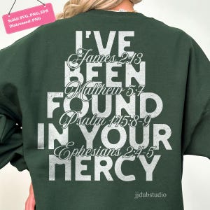 以下が含まれることがあります： 白い文字で「I'VE BEEN FOUND IN YOUR MERCY」と聖書の詩がプリントされた濃い緑色のスウェットシャツ。デザインには「James 2:13, Matthew 5:7, Psalm 145:8-9, Ephesians 2:4-5」が含まれています。「jjdubstudio」のブランド名が下にあります。