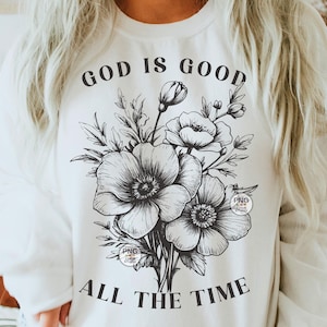 Peut inclure: Sweat-shirt blanc avec un texte noir qui dit "Dieu est bon tout le temps" et un motif floral noir et blanc.