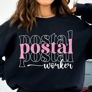May include: Black sweatshirt with the text "postal worker" in pink glitter lettering.