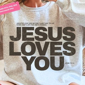 Może przedstawiać: Jasnoszara bluza z napisem "JESUS LOVES YOU" w postarzanym, ciemnobrązowym kroju pisma. Bluza zawiera r&oacute;wnież cytat "GREATER LOVE HAS NO ONE THAN THIS: TO LAY DOWN ONE'S LIFE FOR ONE'S FRIENDS." oraz odniesienie "JOHN 15:13."
