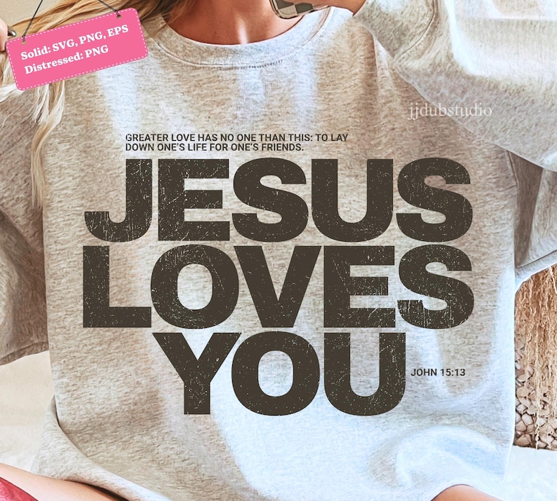Może przedstawiać: Jasnoszara bluza z napisem "JESUS LOVES YOU" w postarzanym, ciemnobrązowym kroju pisma. Bluza zawiera r&oacute;wnież cytat "GREATER LOVE HAS NO ONE THAN THIS: TO LAY DOWN ONE'S LIFE FOR ONE'S FRIENDS." oraz odniesienie "JOHN 15:13."