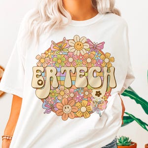 May include: White t-shirt with a colorful retro design featuring the word "ERTECH" surrounded by flowers and butterflies.