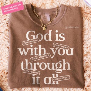 May include: A brown Comfort Colors t-shirt with the message "God is with you through it all" in white text. The shirt has a gold chain necklace. The text includes the phrases "Every Season", "Every Struggle", "Every Doubt", "Every Battle", and "Every Victory".