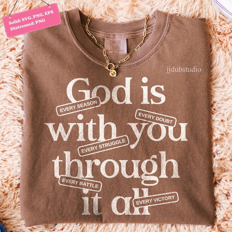 May include: A brown Comfort Colors t-shirt with the message "God is with you through it all" in white text. The shirt has a gold chain necklace. The text includes the phrases "Every Season", "Every Struggle", "Every Doubt", "Every Battle", and "Every Victory".