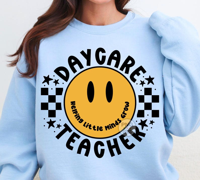 Peut inclure: Sweat-shirt bleu clair avec un motif graphique noir et jaune. Le graphique repr&eacute;sente un visage souriant avec le texte "Daycare Teacher" et "Helping Little Minds Grow" autour du visage.