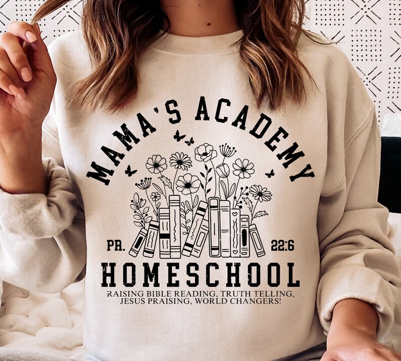 May include: A beige sweatshirt with a black graphic design that says "Mama's Academy" with a stack of books and flowers. The text below the graphic says "PR. 22:6 Homeschool Raising Bible Reading, Truth Telling, Jesus Praising, World Changers!"