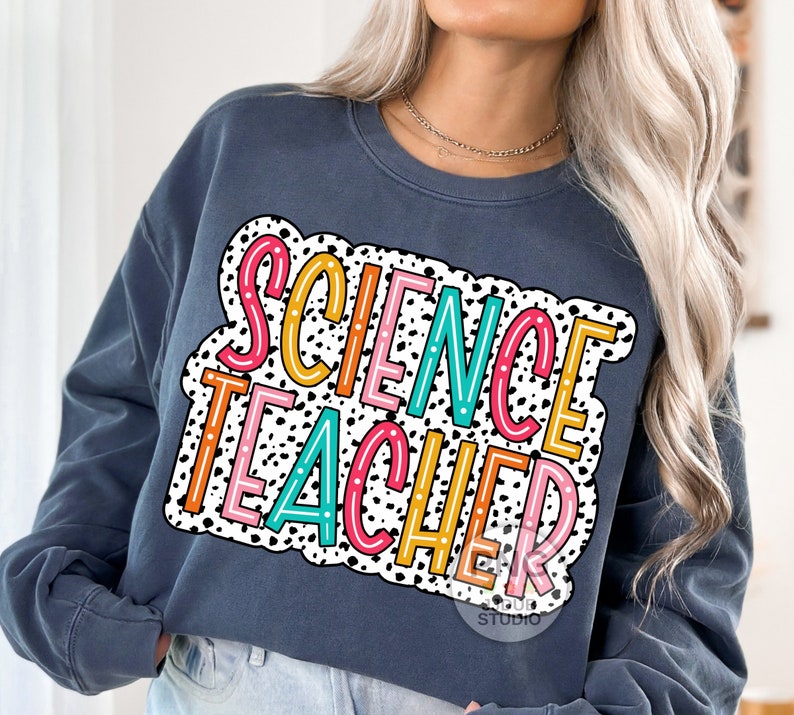 Peut inclure: Un sweat-shirt bleu fonc&eacute; avec un fond &agrave; pois blancs et noirs. Les mots "SCIENCE TEACHER" sont &eacute;crits en lettres color&eacute;es sur le sweat-shirt.