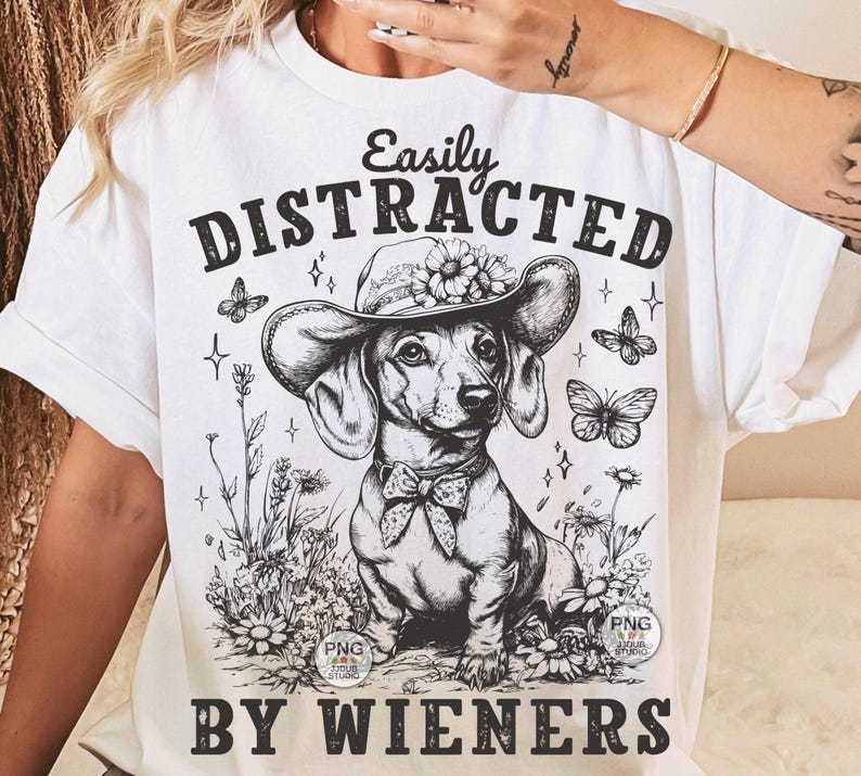 May include: White t-shirt with a black and white illustration of a dachshund wearing a flower crown and the text "Easily Distracted By Wieners".