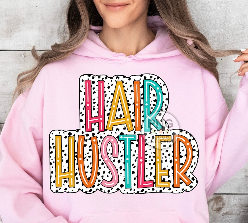 May include: Pink hoodie with a white and black polka dot background and the text "HAIR HUSTLER" in colorful letters.