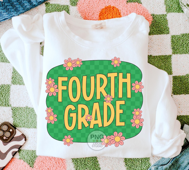 May include: White sweatshirt with a green and white checkered design featuring the text "FOURTH GRADE" in yellow letters and pink flowers around the design.