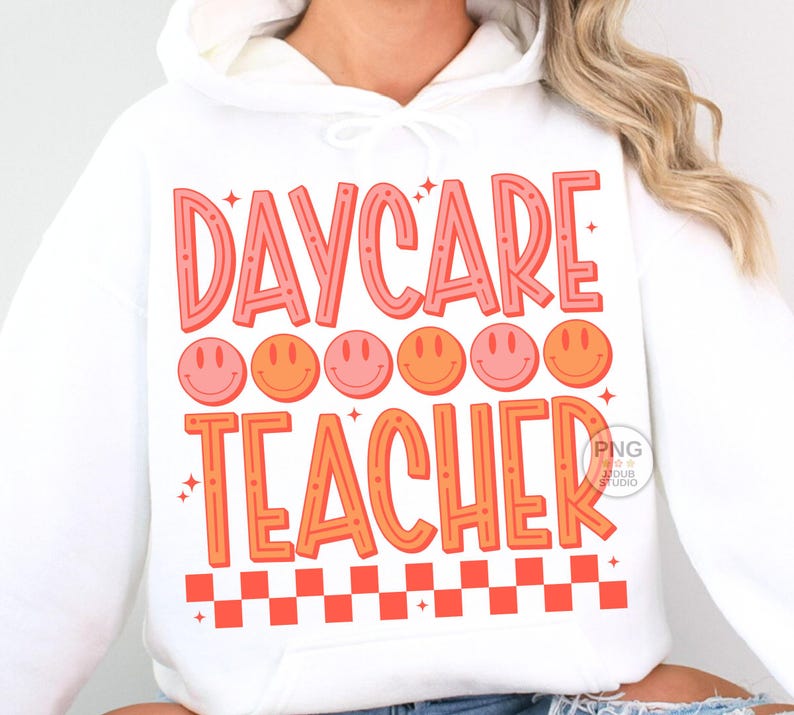 Peut inclure: Sweat-shirt blanc avec le texte "DAYCARE TEACHER" en lettres roses et orange. Le texte est entour&eacute; d'une rang&eacute;e de six visages souriants roses et orange et d'un motif &agrave; carreaux rouge et blanc en bas.