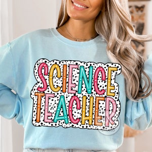 Peut inclure: Sweat-shirt bleu clair avec un motif de pois noirs et blancs et le texte "SCIENCE TEACHER" en lettres color&eacute;es.