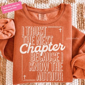 以下が含まれることがあります： 「I TRUST THE NEXT Chapter BECAUSE I KNOW THE AUTHOR」の白文字がプリントされた、錆色のスウェットシャツ。クルーネックと長袖のデザイン。Comfort Colorsブランドのタグが見えます。
