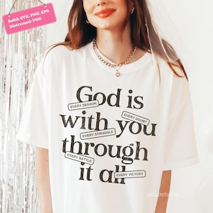 May include: White t-shirt with the message "God is with you through it all" in black text. The design includes the phrases "Every Season," "Every Doubt," "Every Struggle," "Every Battle," and "Every Victory."