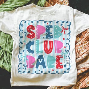 May include: White t-shirt with a colorful graphic that reads "SPEED CLUB BABE." The design features a blue and white striped background with the words in various colors, including red, pink, and blue. The design is framed with a blue scalloped border.