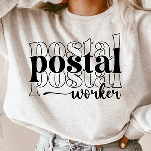 May include: A gray sweatshirt with black text that reads "postal worker" in a layered, stylized font.