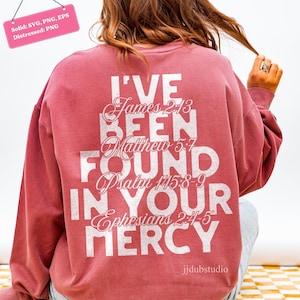 以下が含まれることがあります： くすんだバラ色のスウェットシャツ。白い文字で「I'VE BEEN FOUND IN YOUR MERCY」と書かれています。聖書の詩も含まれています。クルーネックと長袖です。
