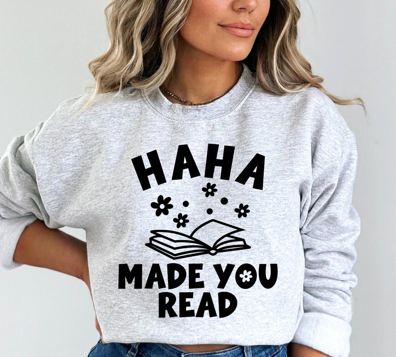 May include: Gray sweatshirt with the text "HAHA MADE YOU READ" in black lettering. The text is surrounded by small black flower illustrations.
