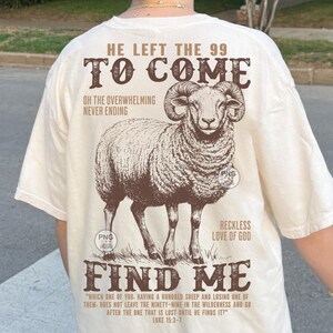 May include: Cream-coloured t-shirt with a detailed illustration of a ram. The shirt features the text "HE LEFT THE 99 TO COME" and "FIND ME", along with a Bible verse. The design is in brown.