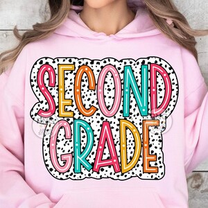 May include: Pink hoodie with a black and white polka dot background and the text "SECOND GRADE" in colorful letters with a white outline.