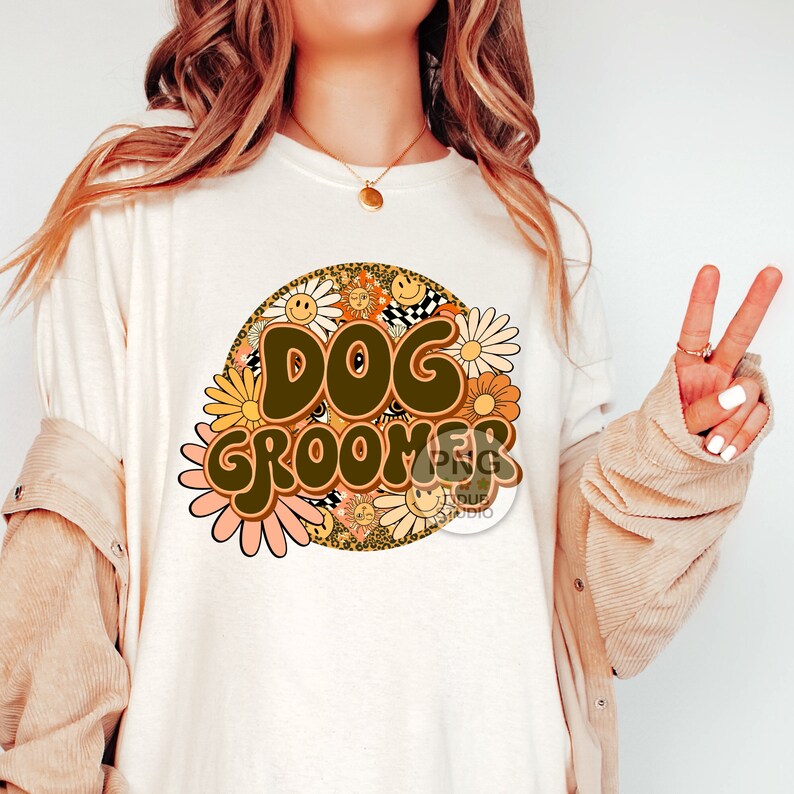 May include: A white t-shirt with a brown and yellow graphic design that says "Dog Groomer" surrounded by flowers and a leopard print pattern.