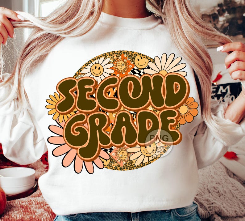 May include: White sweatshirt with a retro-style design featuring the words "Second Grade" in brown letters surrounded by colorful flowers and smiley faces.