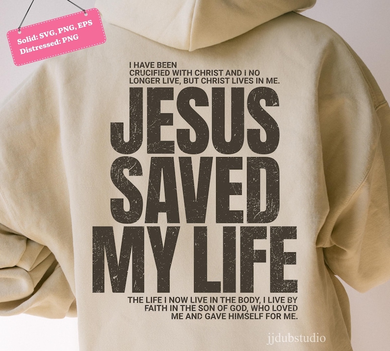 Może przedstawiać: Beżowa bluza z kapturem z napisem "JESUS SAVED MY LIFE" dużymi, zniszczonymi, ciemnobrązowymi literami. Nad tekstem znajdują się słowa "I HAVE BEEN CRUCIFIED WITH CHRIST AND I NO LONGER LIVE, BUT CHRIST LIVES IN ME."
