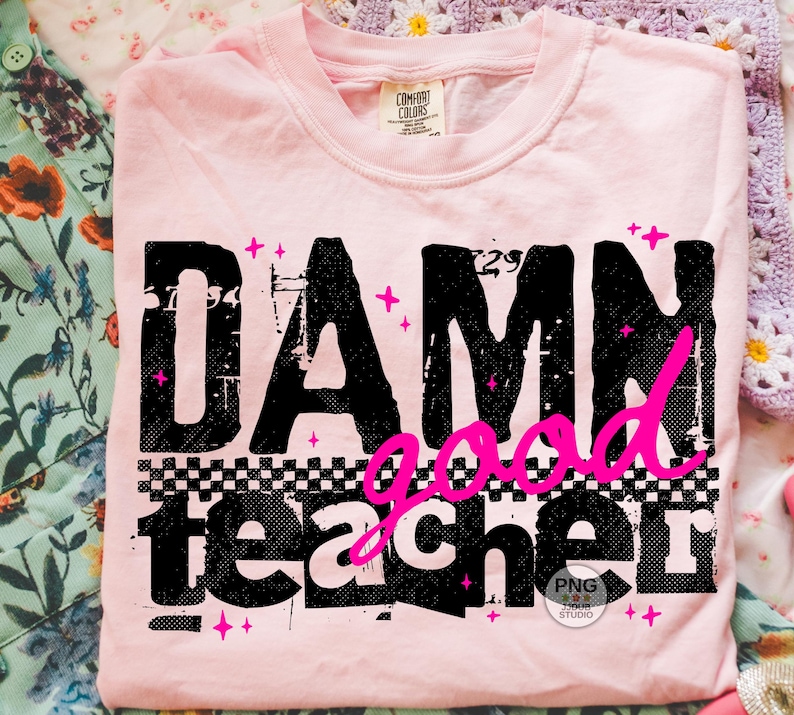 以下が含まれることがあります： 黒とピンクで「DAMN good teacher」と書かれた、薄いピンク色のTシャツ。テキストは、市松模様とピンクの星のアクセントが付いた、使い古されたような外観です。