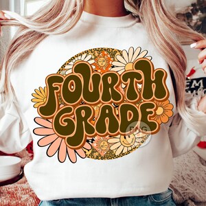 May include: A white sweatshirt with a retro-style graphic design featuring the text "FOURTH GRADE" in brown letters surrounded by colorful flowers and suns.