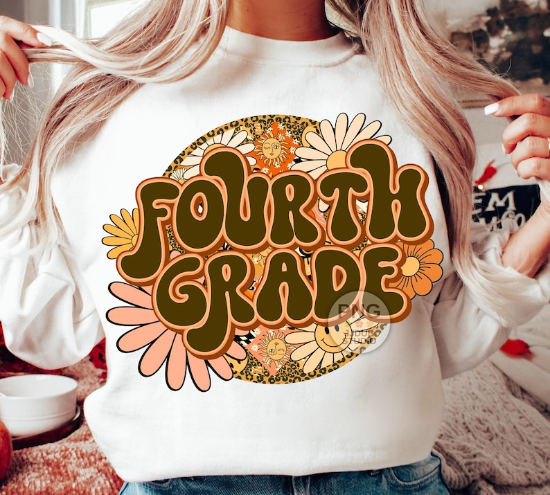 May include: A white sweatshirt with a retro-style graphic design featuring the text "FOURTH GRADE" in brown letters surrounded by colorful flowers and suns.