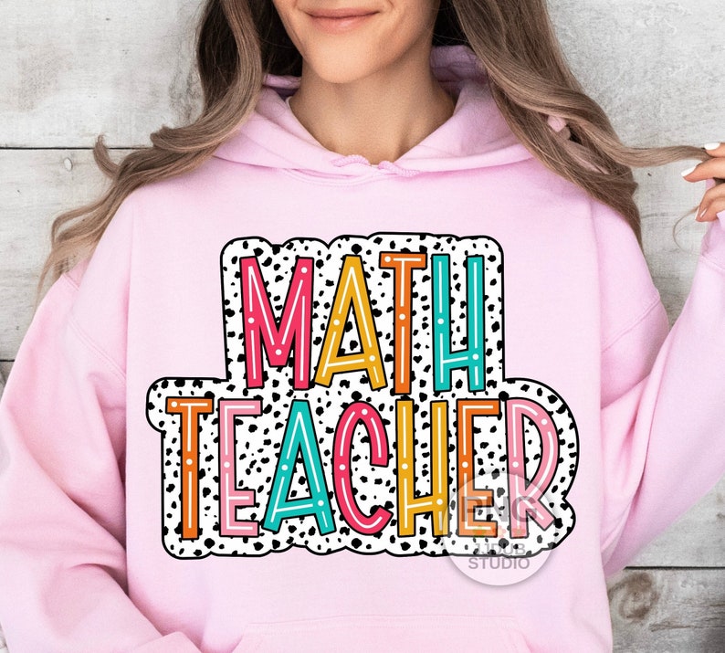 Op de afbeelding: Roze hoodie met een kleurrijke afbeelding met de tekst "MATH TEACHER" in een zwart-wit stippenpatroon.