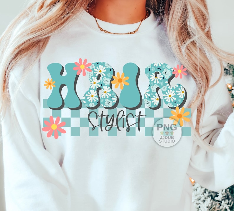 May include: A white sweatshirt with a blue and white floral design that says "Hair Stylist" in a retro font. The design is on a checkered background with pink and yellow flowers.