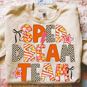 May include: A beige sweatshirt with the words "SPED DREAM TEAM" in orange, black, pink, and white. The letters have various patterns, including flowers, stripes, and checkerboard. A pink star and a lightning bolt are also featured.