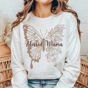 May include: A white sweatshirt with a brown butterfly design and the text "Blessed Mama" printed on the front.