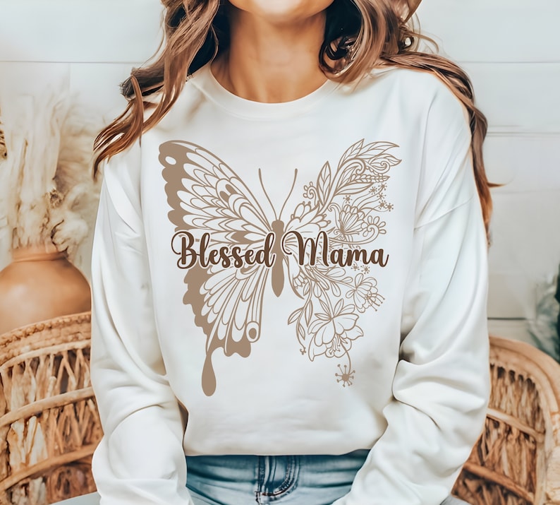 May include: A white sweatshirt with a brown butterfly design and the text "Blessed Mama" printed on the front.