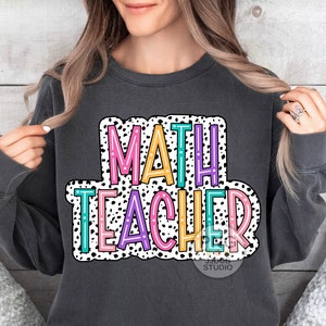 Op de afbeelding: Een antracietkleurig sweatshirt met een witte, zwarte en kleurrijke afbeelding waarop "MATH TEACHER" staat in een vetgedrukte, omrande lettertype. De afbeelding is omgeven door een wit stippenpatroon.