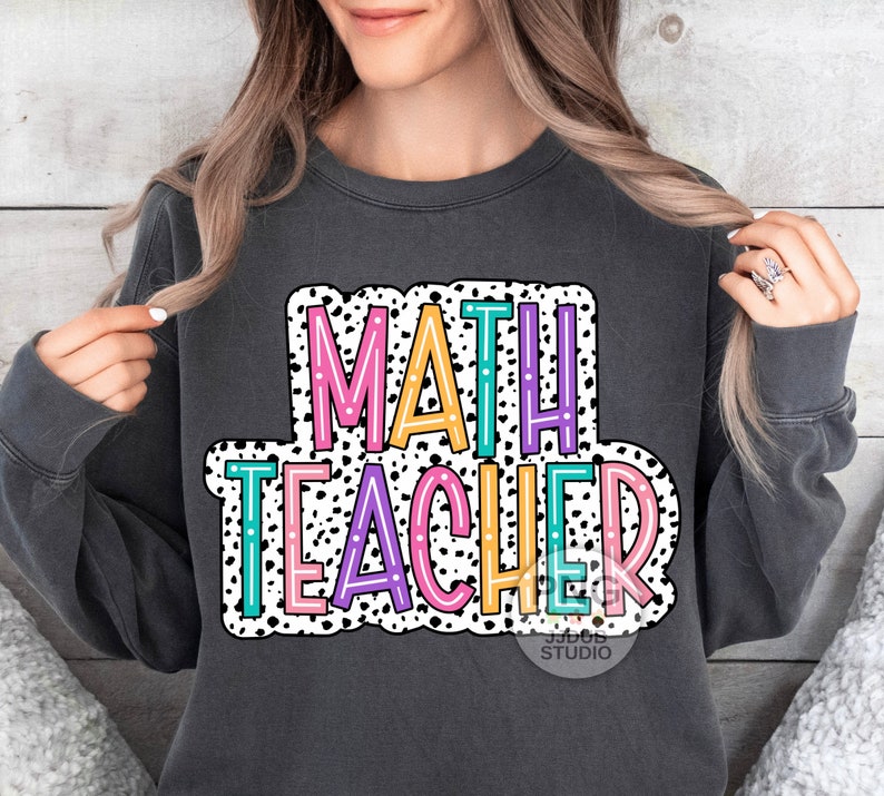 Op de afbeelding: Een antracietkleurig sweatshirt met een witte, zwarte en kleurrijke afbeelding waarop "MATH TEACHER" staat in een vetgedrukte, omrande lettertype. De afbeelding is omgeven door een wit stippenpatroon.