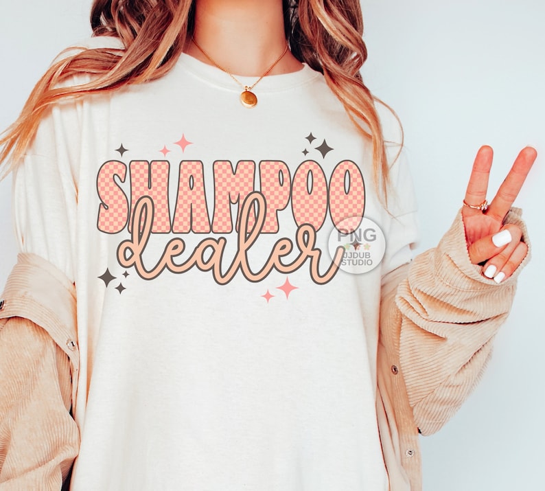 May include: A white t-shirt with the text "SHAMPOO dealer" in pink and brown letters with a checkered pattern. The text is surrounded by small pink and black stars.