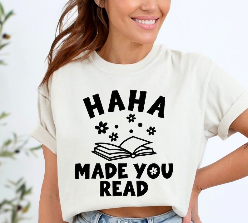 May include: White t-shirt with black text that reads "HAHA MADE YOU READ" with a book and flowers graphic.